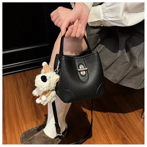 Detail of black pebbled leather bucket bag with silver twist lock and cute puppy charm