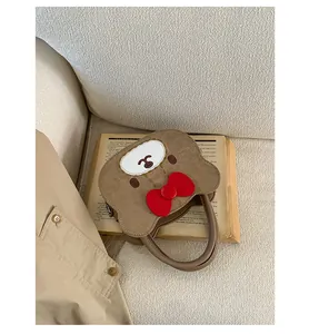 Detailansicht einer braunen Cartoon-Bär-Tasche mit roter Schleife und Rundgriff