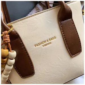 Detailaufnahme der Retro-Beuteltasche mit Goldlogo und Holzperlen-Anhänger-Zubehör