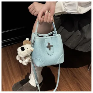 Close-up of light blue bucket bag with silver turn-lock and cute plush puppy charm