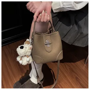 Detail of brown lychee grain leather bucket bag with silver twist lock and puppy charm