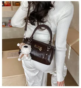 Dunkelbraune Boston-Tasche aus Lackleder mit einem süßen Plüsch-Hundeanhänger