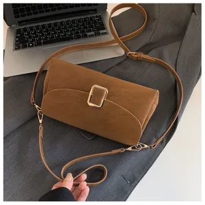 Detail view of brown suede shoulder bag with gold metal buckle on professional background