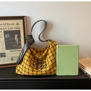 Detailed view of yellow plaid tote bag with heart embroidery and knotted leather strap