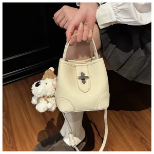 Detail of off-white bucket bag featuring lychee grain leather and a cute bear charm