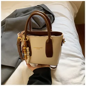 Detail der minimalistischen Beuteltasche mit Holzperlenanhänger und Kontrastriemen