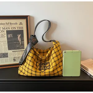 Close-up of checkered tote bag featuring a leather strap with a decorative oversized knot