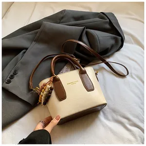 Detail der minimalistischen Beuteltasche mit Perlenanhänger auf grauem Blazer