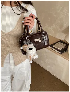 Detail der dunkelbraunen glänzenden Boston Bag mit Plüschhund-Anhänger und Silberakzenten