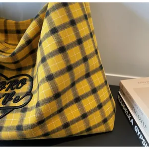 Detail of yellow plaid tote bag with heart embroidery and Hero Love lettering