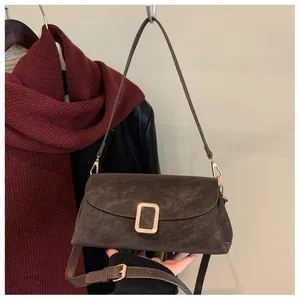 Detail of a brown suede crossbody bag with elegant gold metal buckle for daily commute