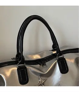 Gros plan du sac cabas argenté avec anses noires et ornements en forme d'étoile