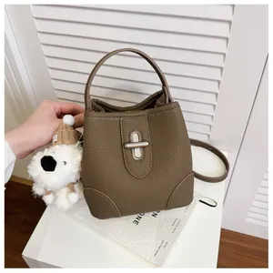 Detail of brown pebble leather bucket bag with metal twist lock and cute bear charm