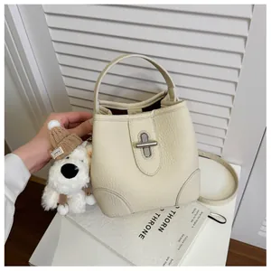 Detail of off-white lychee grain leather bucket bag with silver twist lock and plush charm