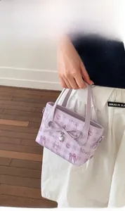 Detail view of purple plaid handbag with bow, heart charm and cute cartoon patterns