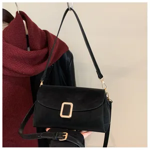 Detail of black suede shoulder bag with golden buckle on autumn fashion background