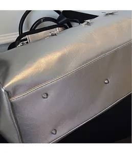 Gros plan du fond de sac argenté brillant avec rivets métalliques et texture plissée