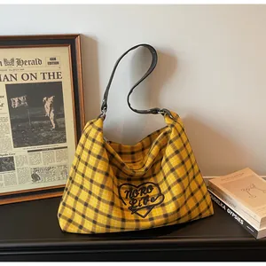 Detail of checkered tote bag featuring black heart embroidery and thin leather shoulder strap