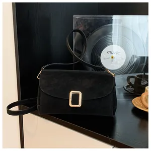 Close-up of black suede square bag with golden buckle on a vintage artistic background