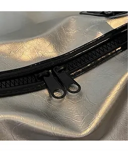Détail de la double fermeture éclair noire sur tissu argenté métallisé plissé