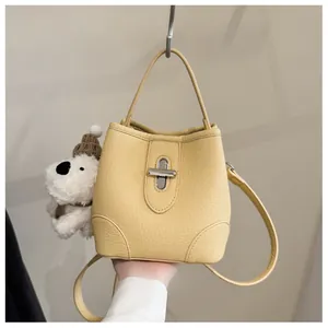 Detail of pale yellow bucket bag with lychee grain leather and silver metal twist lock