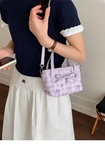 Detail of lavender plaid bucket bag with cartoon bear prints and bow charm on model