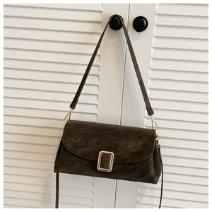 Detailed close-up of the dark brown suede texture and large gold buckle on this square bag