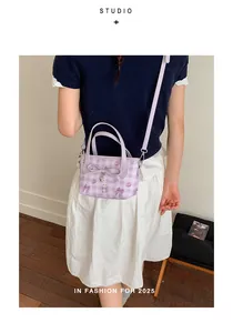 Detail of purple plaid bucket bag with cartoon prints and bow worn as crossbody bag