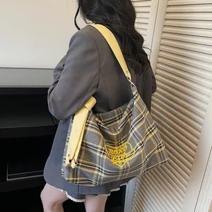 Plaid tote bag with yellow heart embroidery and wide shoulder strap shown on model
