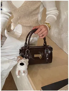 Detail der dunkelbraunen Boston-Tasche mit Plüschbär-Anhänger und Herz-Metall-Tag