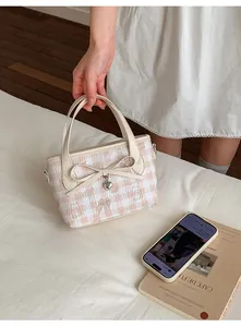 Detail view of the pink checkered bucket bag featuring bear prints and a heart pendant