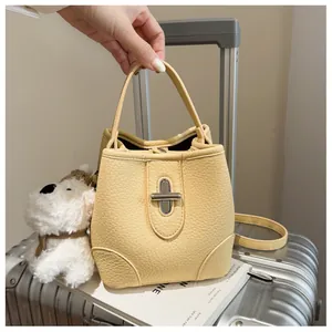Detail of light yellow bucket bag with lychee texture and silver turn-lock closure