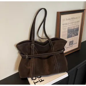Detail der dunkelbraunen Ledertasche mit weißen Kontrastnähten und Zierriemen