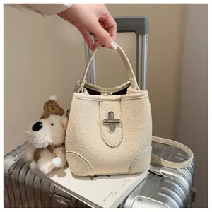Detail of beige bucket bag with pebble leather texture and elegant metal twist lock