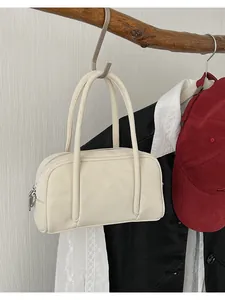 Dettaglio di una borsa quadrata color crema appesa con accessori lifestyle moderni