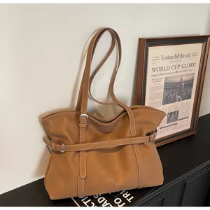 Detailansicht einer braunen Shopper Tasche mit Zierriemen auf einem edlen Schrank