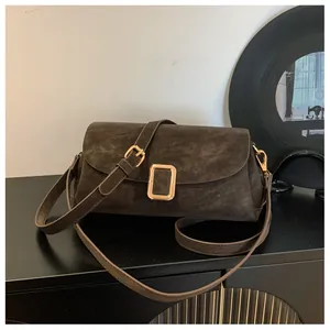 Detail of vintage textured square shoulder bag with gold rectangular buckle and strap