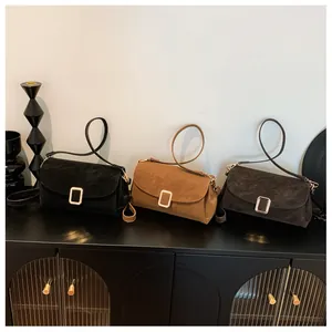 Detailed view of square suede crossbody bags with gold buckles in black and brown colors