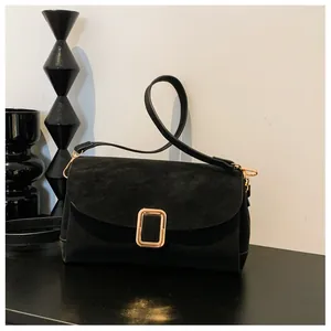 Macro detail of black matte square bag with gold metal buckle and suede texture