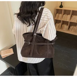 Details einer braunen Retro-Tragetasche mit weißen Kontrastnähten und Gürtelschnalle