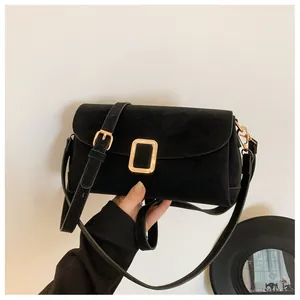 Detailed close-up of a black matte flap bag with gold hardware and an adjustable shoulder strap