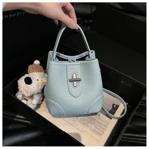 Detail of light blue pebble leather bucket bag featuring a silver metal twist lock closure