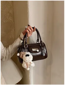 Nahaufnahme der braunen glänzenden Boston Bag mit Metallschnalle und Plüschanhänger