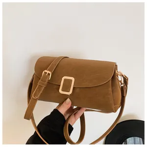 Detail of vintage brown suede crossbody bag with elegant gold metal buckle and strap
