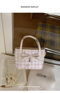 Detailed view of pink plaid bucket bag with cartoon prints and heart pendant on a table