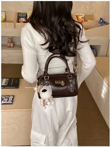 Dunkelbraune Boston-Tasche mit Vintage-Schnalle und Plüsch-Hundeanhänger am Modell