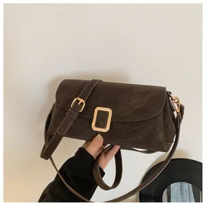 Detailed macro shot of dark brown suede shoulder bag with golden metallic buckle