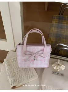 Detail of pink plaid bucket bag featuring cute cat prints and a silver heart pendant