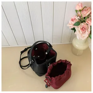 Detail of black lychee grain bucket bag with burgundy drawstring pouch and long strap