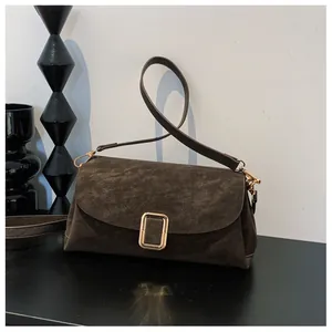 Macro shot of dark brown suede square bag featuring a prominent gold rectangular metal buckle
